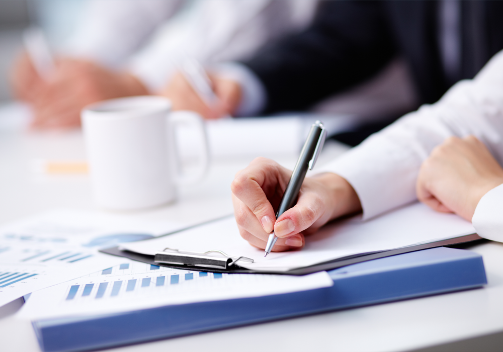 Vrouw schrijft met pen op financiele documentatie Vrouw schrijft met pen op financiele documentatie